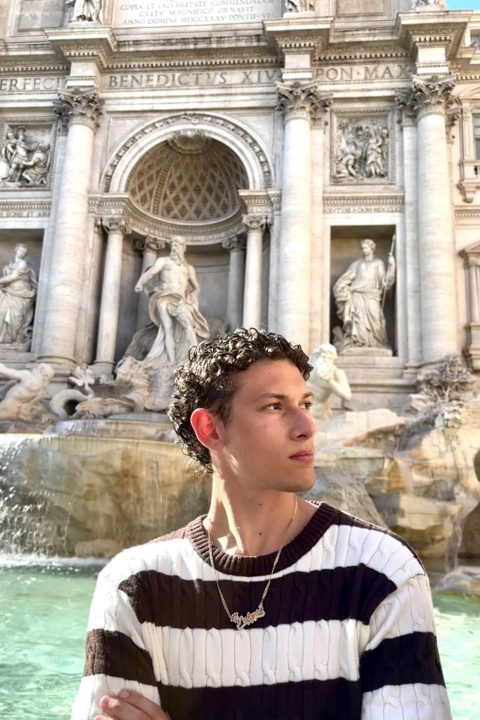 Ricardo posing  in front of a building with may statues